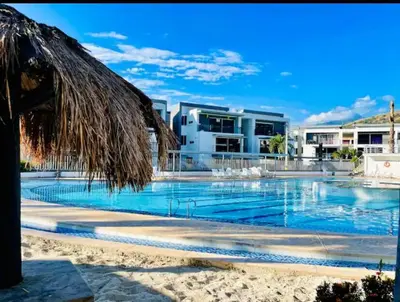 a swimming pool with a straw umbrella and a resort at Apartasol por días en condominio ciudadela Santa Fe de Antioquia in Santa Fe de Antioquia