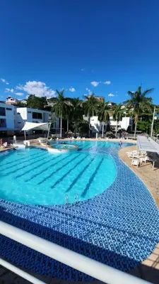 a large swimming pool with blue water and palm trees at Apartasol por días en condominio ciudadela Santa Fe de Antioquia in Santa Fe de Antioquia