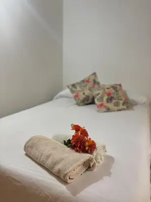 a white bed with a towel and flowers on it at Confort y Estilo en el Centro de Medellín Perfecto para tu Estancia in Medellín