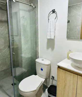 a bathroom with a toilet and a glass shower at Apartamentos laureles estadio 101 ED MILA in Medellín