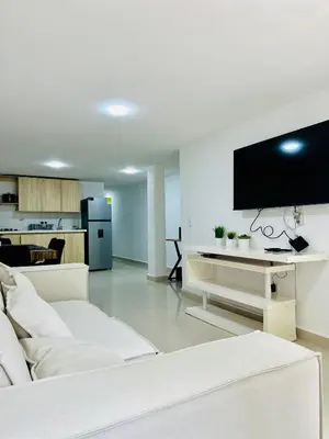 a living room with a white couch and a flat screen tv at Apartamentos laureles estadio 101 ED MILA in Medellín