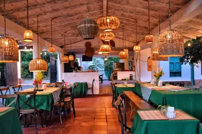 a restaurant with green tables and chairs and chandeliers at Palma Serena Finca Hotel in Santa Fe de Antioquia