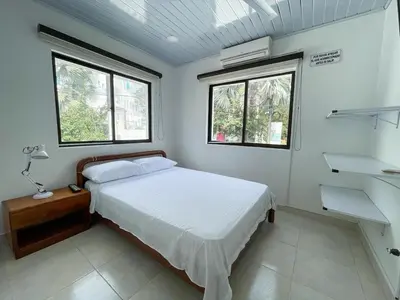 a small bedroom with a bed and two windows at Plaza Blanca 2 cabaña en el Santorini Colombiano in Doradal