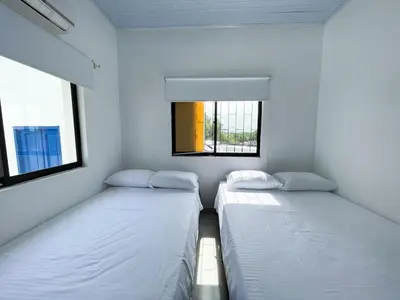 two beds in a small room with two windows at Plaza Blanca 2 cabaña en el Santorini Colombiano in Doradal