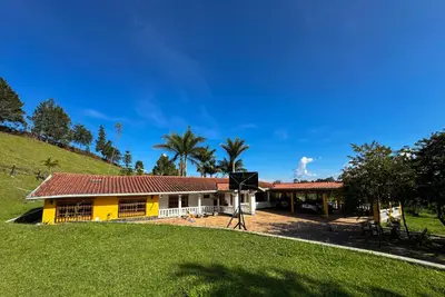 a yellow and white house with palm trees and a hill at Casa Finca Villa Laura 158 in Rionegro