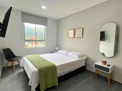 a bedroom with a bed and a chair and a window at Apartamento Familiar en Sabaneta cerca al parque in Sabaneta