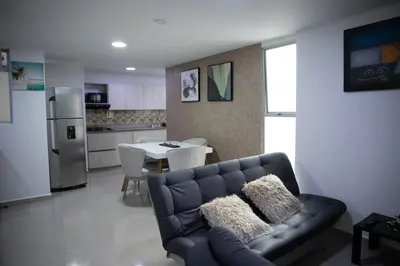 a living room with a couch and a kitchen with a table at 901-Apartamento Central Parque de Sabaneta in Sabaneta