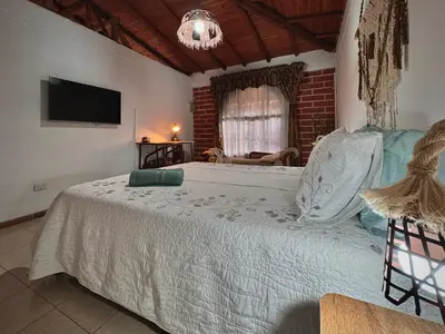 a bedroom with a large bed with a tv on the wall at Casa Amaru Rooms in Guarne