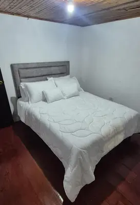 a bed with white sheets and pillows in a room at Hospedaje en Marulanda in Marulanda