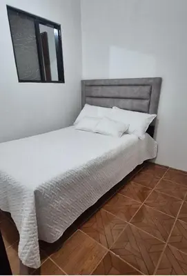 a bed with white sheets and a mirror in a room at Hospedaje en Marulanda in Marulanda