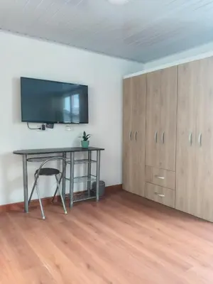 a room with a desk and a tv on a wall at La Arboleda Apartamento in Manizales