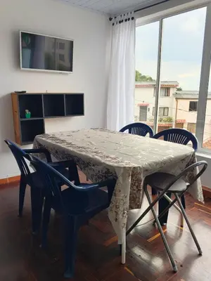 a dining room table with chairs and a window at La Arboleda Apartamento in Manizales