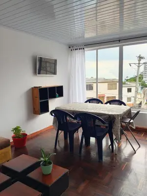 a living room with a table and chairs and a large window at La Arboleda Apartamento in Manizales