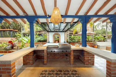 an outdoor kitchen with a brick wall and blue beams at Sweet Helen Casa Santa in Rionegro