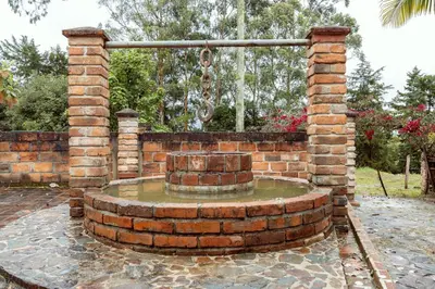 a brick wall with a fountain in a yard at Sweet Helen Casa Santa in Rionegro