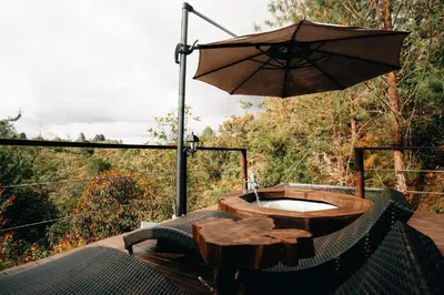 a wooden table with an umbrella on a deck at Forest El Retiro, cabañas en el bosque in El Retiro
