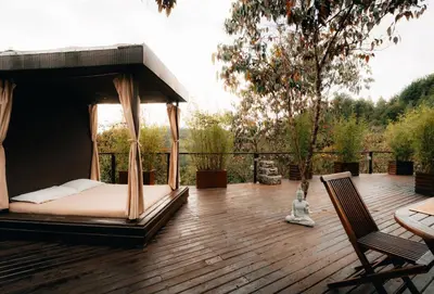a porch with a bed on a wooden deck at Forest El Retiro, cabañas en el bosque in El Retiro