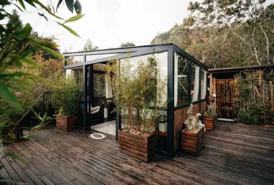 a greenhouse with potted plants on a wooden deck at Forest El Retiro, cabañas en el bosque in El Retiro