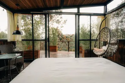 a bedroom with a large bed and a large window at Forest El Retiro, cabañas en el bosque in El Retiro