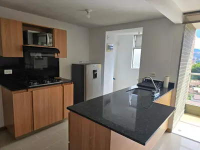 a kitchen with a black counter top and a refrigerator at Amoblado Belen Avenida in Medellín