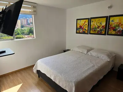 a bedroom with a bed and three paintings on the wall at Amoblado Belen Avenida in Medellín