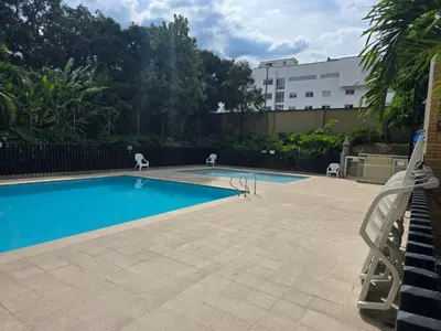 a swimming pool with two lawn chairs next to a building at Amoblado Belen Avenida in Medellín