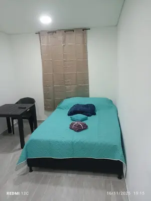 a bedroom with a bed with a blue blanket and a table at Alojamientos Jamar in Rionegro