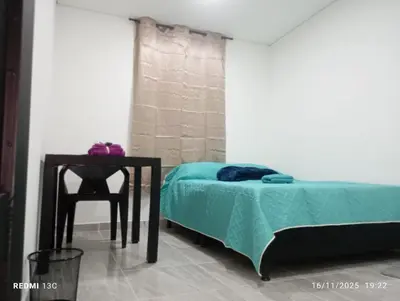 a bedroom with a bed and a table with a chair at Alojamientos Jamar in Rionegro