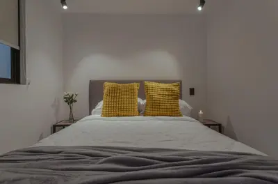 a bedroom with a bed with two yellow pillows at El lienzo Blanco en Medellin in Envigado