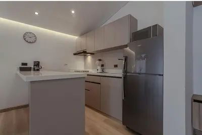 a kitchen with white cabinets and a stainless steel refrigerator at El lienzo Blanco en Medellin in Envigado