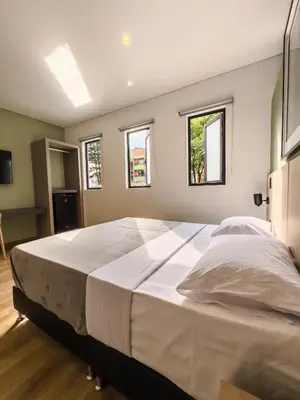 a large white bed in a room with windows at Habitat Ochentayuno in Medellín