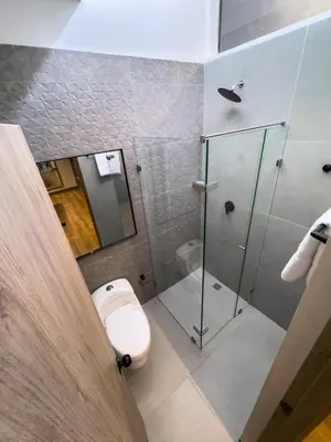 a bathroom with a toilet and a glass shower at Habitat Ochentayuno in Medellín