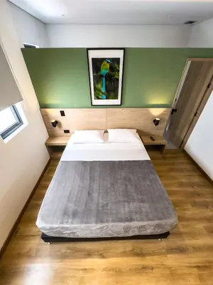a large bed in a room with a green wall at Habitat Ochentayuno in Medellín