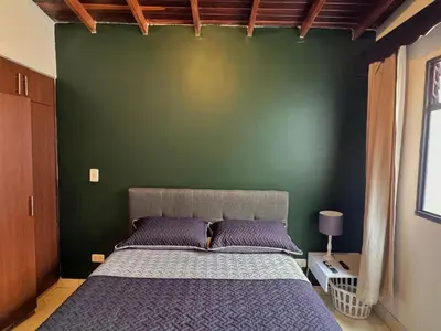 a bedroom with a bed with a green wall at Apartamento Espacioso Belen Alameda cerca a Laureles y unidad deportiva de Belen in Medellín