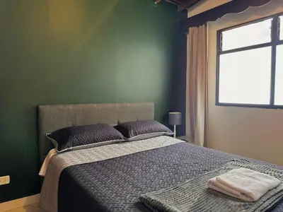 a bedroom with a bed with green walls and a window at Apartamento Espacioso Belen Alameda cerca a Laureles y unidad deportiva de Belen in Medellín