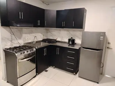 a kitchen with black cabinets and a stainless steel refrigerator at Confortable apartamento en el corazón de Medellín in Medellín