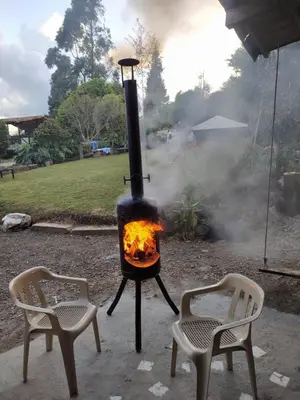 two chairs and a stove with a fire in a yard at Casa Finca Cerca a Medellin y Aeropuerto JMC in Guarne