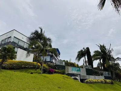 a large house on a hill with palm trees at Villa Salomé in Guatapé in La Pradera