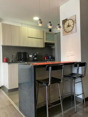a kitchen with a counter with stools and a clock on the wall at Beautiful Loft close to airport,pool gym & parking in Rionegro