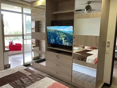 a bedroom with a large entertainment center with a television at Beautiful Loft close to airport,pool gym & parking in Rionegro