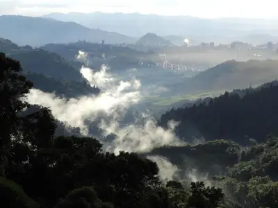 a view of a valley with clouds in the hills at Cabaña privada Reserva Rio Blanco Manizales in Manizales