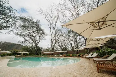 a swimming pool with chairs and an umbrella at Holistic EcoHotel in Santa Fe de Antioquia