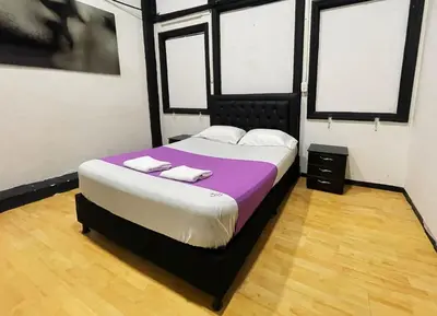 a bedroom with a bed with purple sheets and white pillows at Hotel Palacio in Manizales