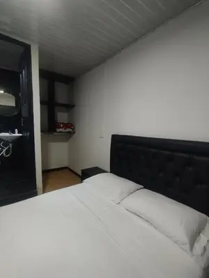 a bedroom with a white bed with a black headboard at Hotel Palacio in Manizales