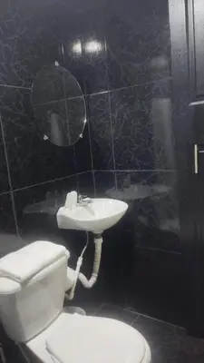 a black tiled bathroom with a toilet and a sink at Hotel Palacio in Manizales