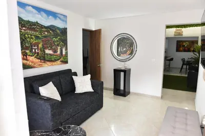 a living room with a black couch and a painting at Laureles Sweet Home in Medellín