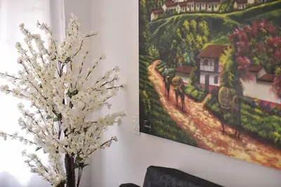 a painting on a wall next to a vase with white flowers at Laureles Sweet Home in Medellín