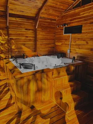 a bath tub in a wooden room with a tv at Refugio la Arboleda in San Rafael