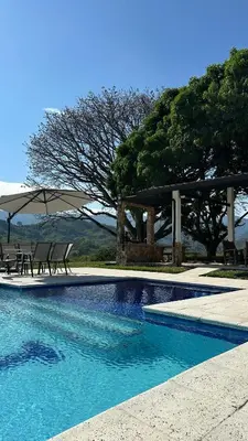 a swimming pool with two chairs and an umbrella at Hacienda La Tranquera in Anserma