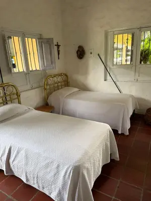 a bedroom with two beds with white sheets and windows at Hacienda La Tranquera in Anserma